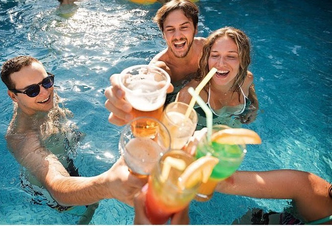 Amigos brindando en una piscina con bebidas de colores