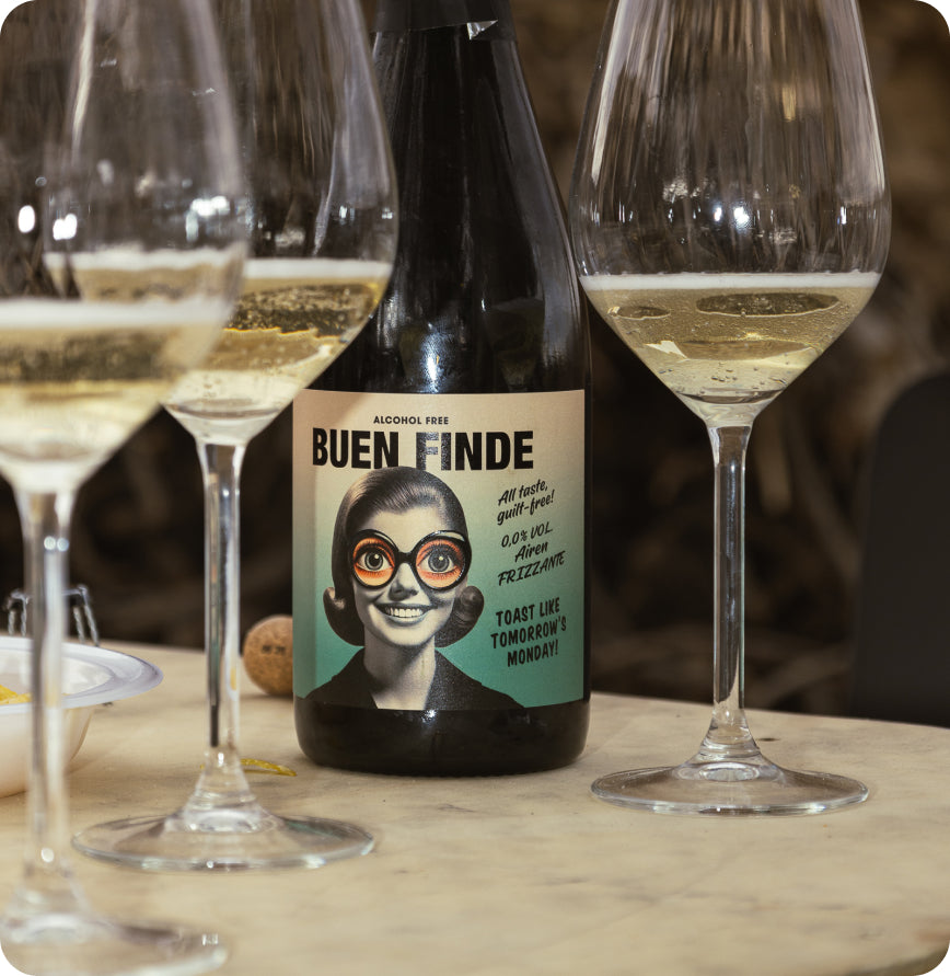 Botella de Buen Finde junto a copas de vino en una mesa, invitando a disfrutar de un brindis sin alcohol